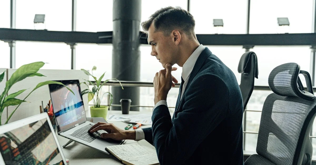 Un homme professionnel analysant des données du marché boursier dans un espace de travail moderne avec des ordinateurs portables.