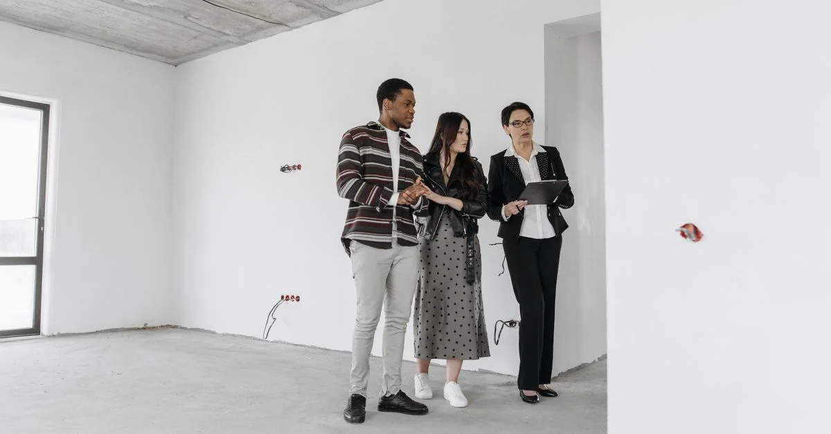 Agent immobilier avec des clients explorant l'intérieur d'un appartement inachevé.