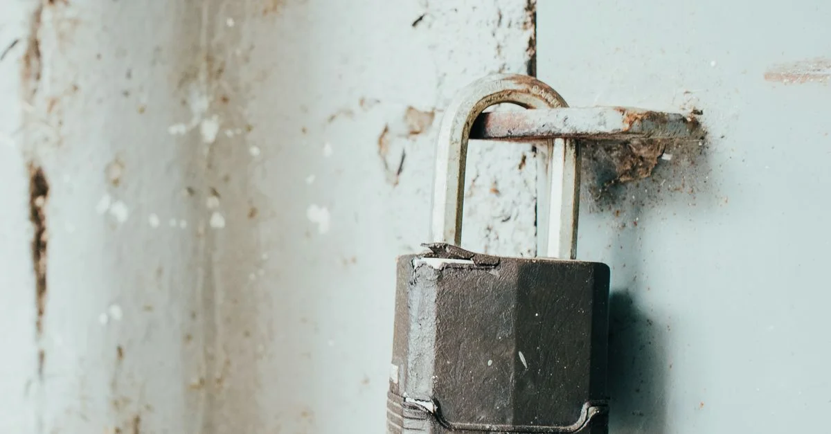 Gros plan détaillé d'un cadenas rouillé sécurisant une porte vieillie, mettant en avant l'âge et la texture.