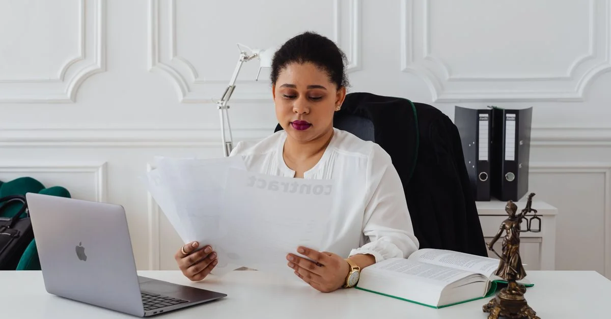 Femme d'affaires confiante analysant des contrats à son bureau propre et organisé.