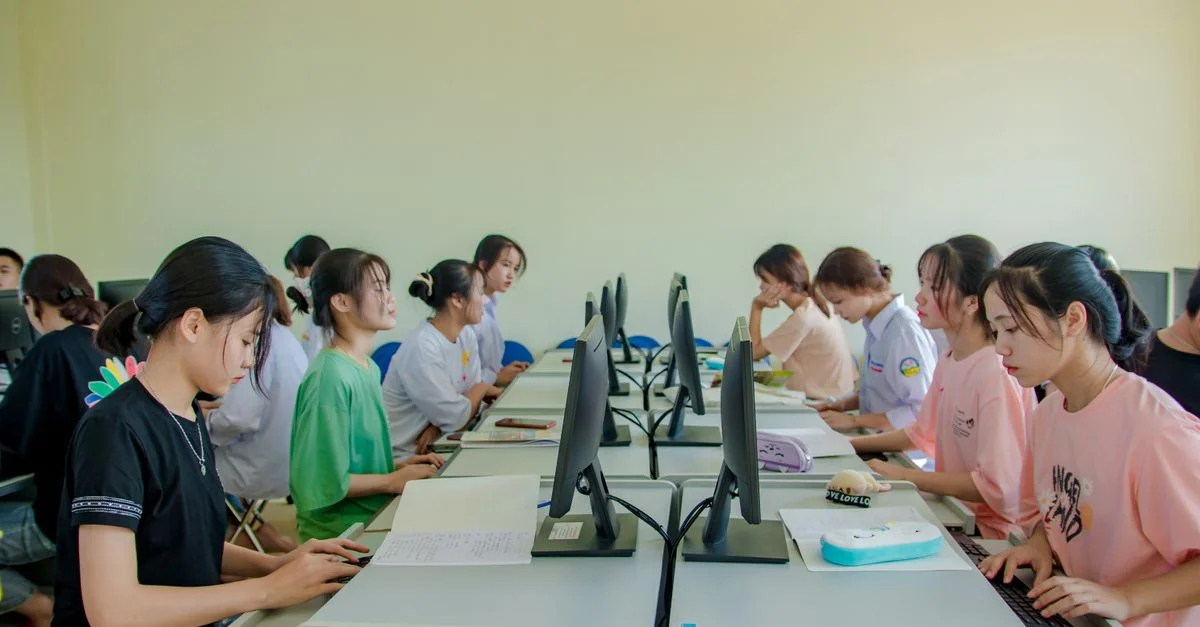 Groupe d'étudiantes étudiant sur des ordinateurs dans une salle de classe.