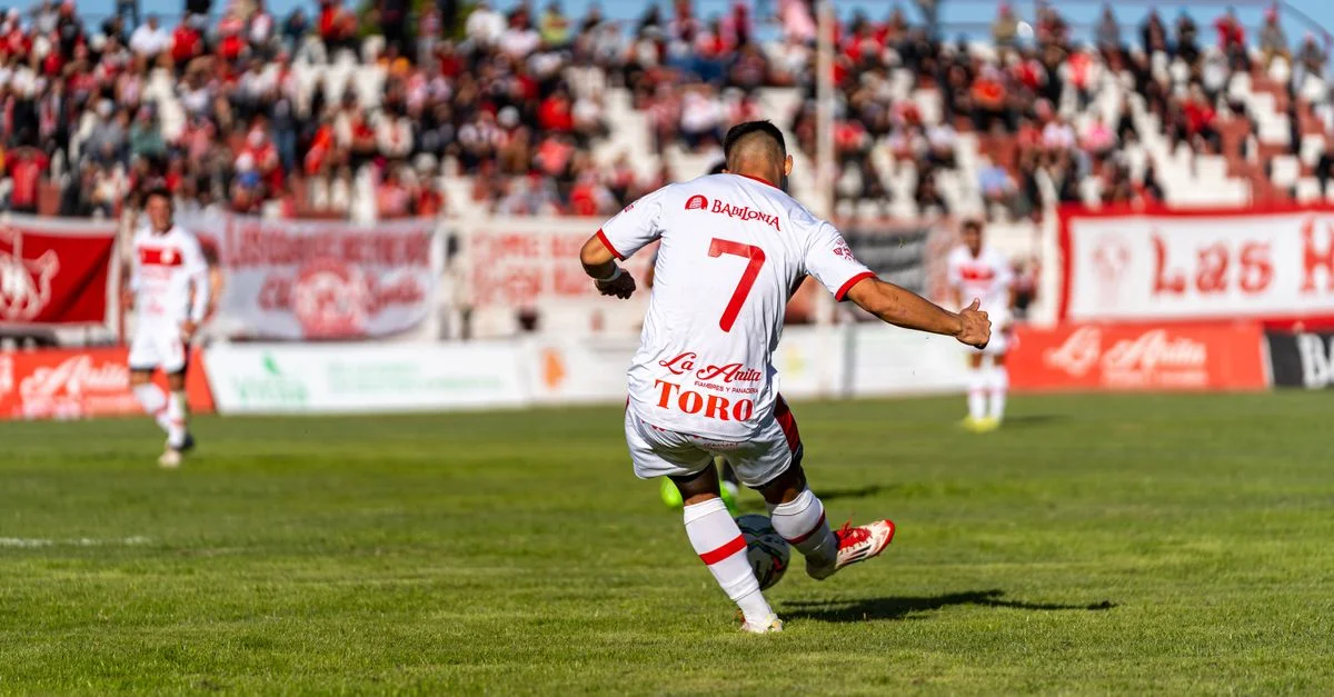 Joueur de football professionnel en pleine action lors d'un match animé, démontrant un esprit sportif dynamique par une journée ensoleillée.