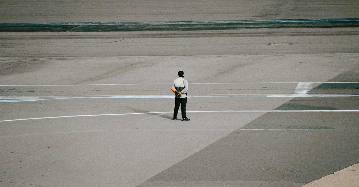 Membre du personnel au sol en uniforme se tenant sur la piste de l'aéroport prêt pour les opérations aéronautiques.
