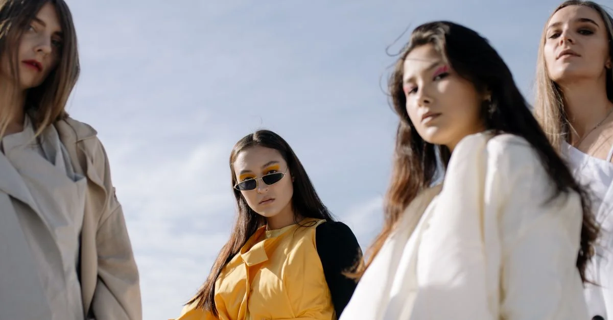 Femmes à la mode posant avec confiance dans des tenues chics sous un ciel dégagé.