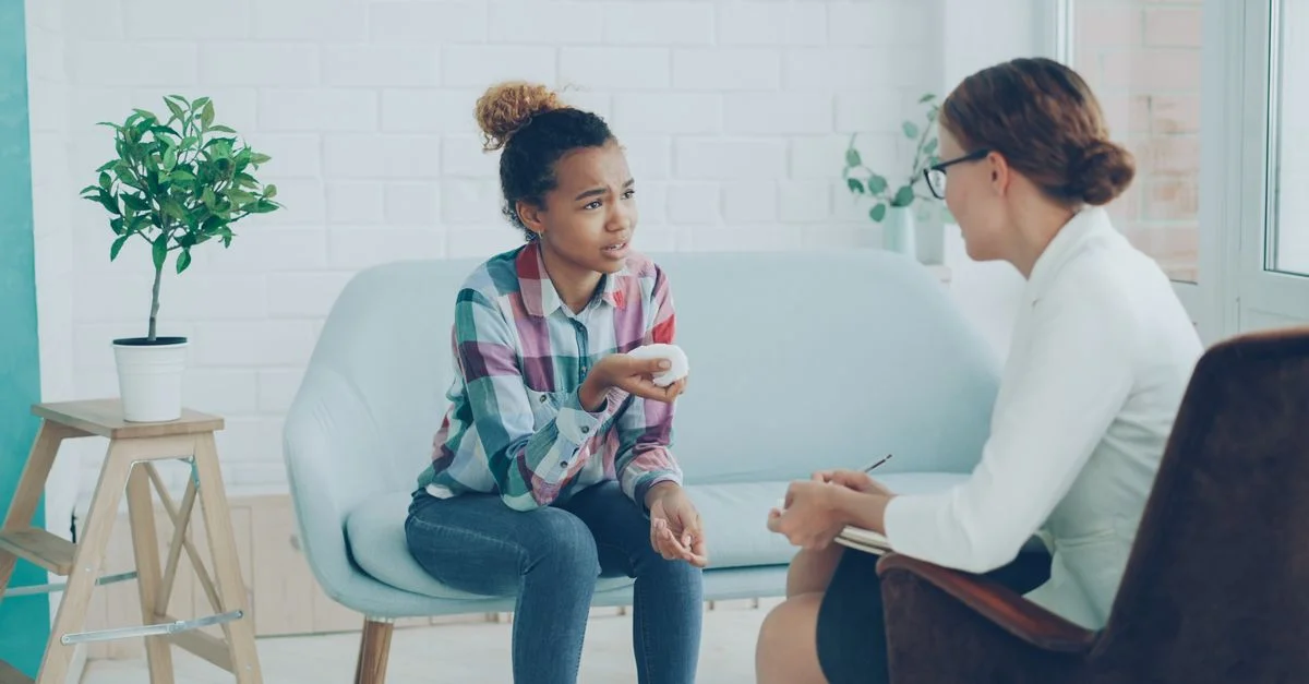 Une jeune femme discute avec une conseillère lors d'une séance. Bureau moderne et lumineux.