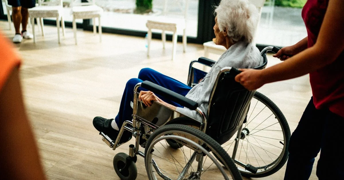 Un aidant aide une personne âgée dans un fauteuil roulant dans une maison de retraite à Prague, République tchèque.