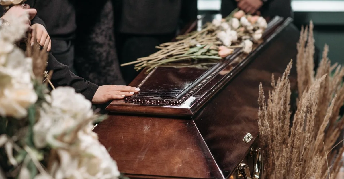 Un moment funéraire poignant avec des proches rassemblés autour d'un cercueil décoré de fleurs.