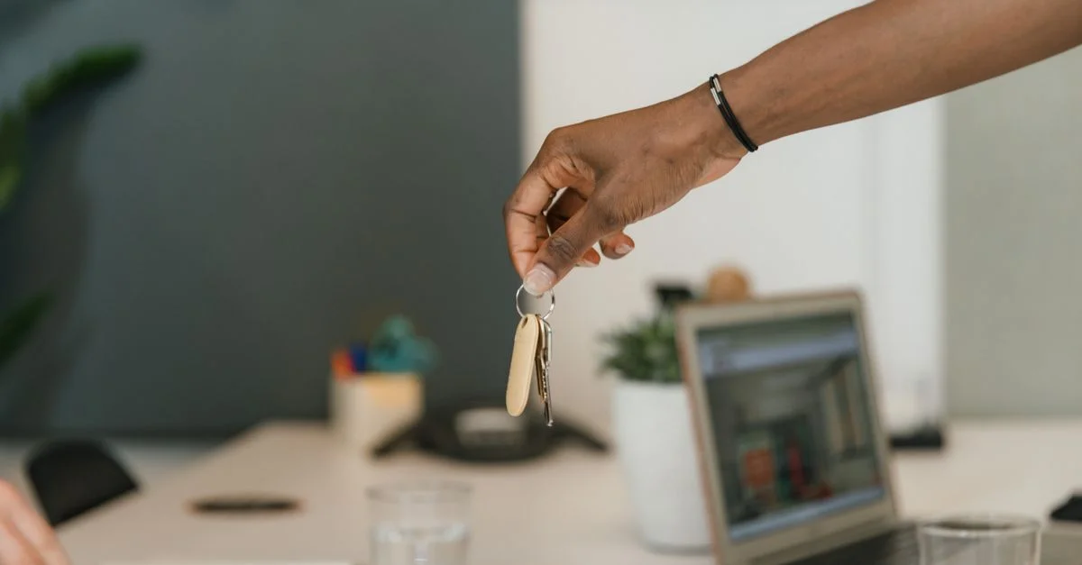 Gros plan sur une poignée de main échangeant des clés dans un environnement de bureau.