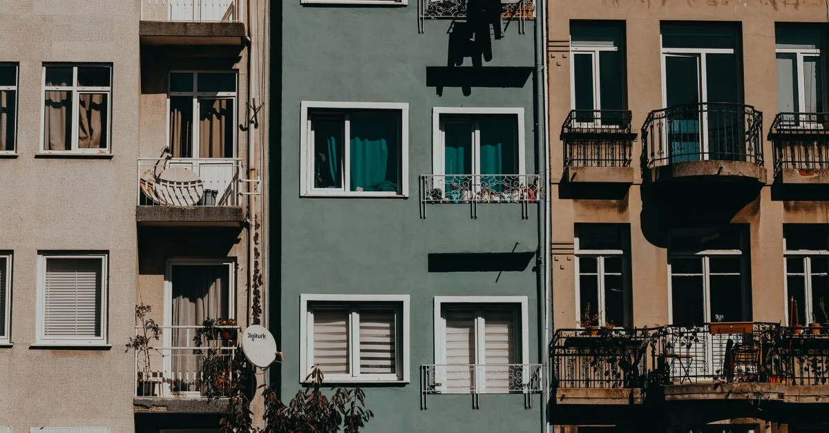 Une rangée d'immeubles d'appartements urbains avec balcons et façades variées profitant du soleil, illustrant l'architecture de la ville.