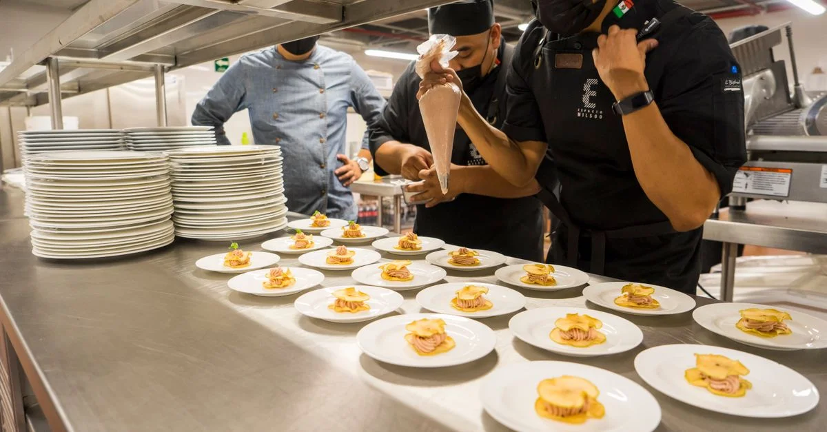 Équipe de chefs préparant créativement des hors-d'œuvre gourmets dans une cuisine commerciale.