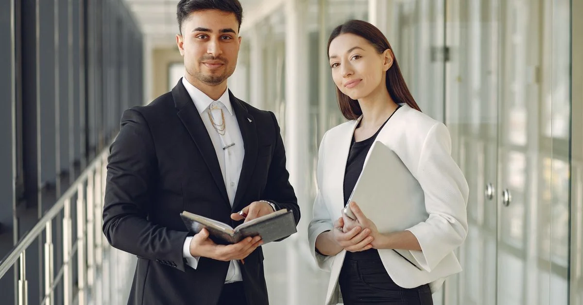 Professionnels du secteur se tenant confiants dans un couloir de bureau moderne, prêts pour une réunion.