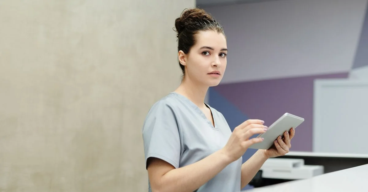 Réceptionniste professionnel utilisant un appareil tablette à un bureau d'accueil moderne.