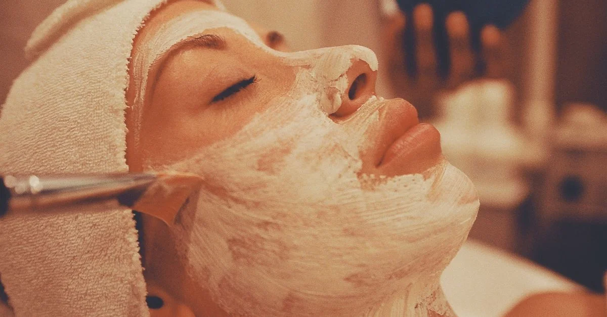 Un soin du visage apaisant de type spa, avec une femme recevant l'application d'un masque facial luxueux.