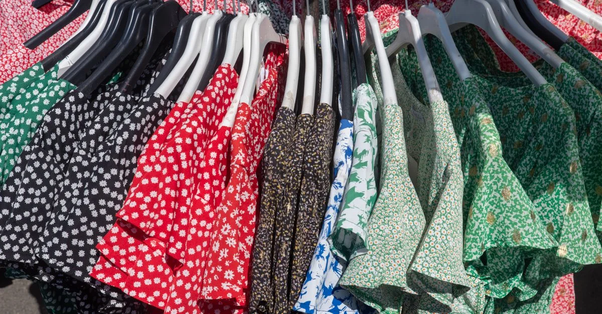 Une collection éclatante de robes à fleurs et à motifs, suspendues à un portant, présente des styles variés.