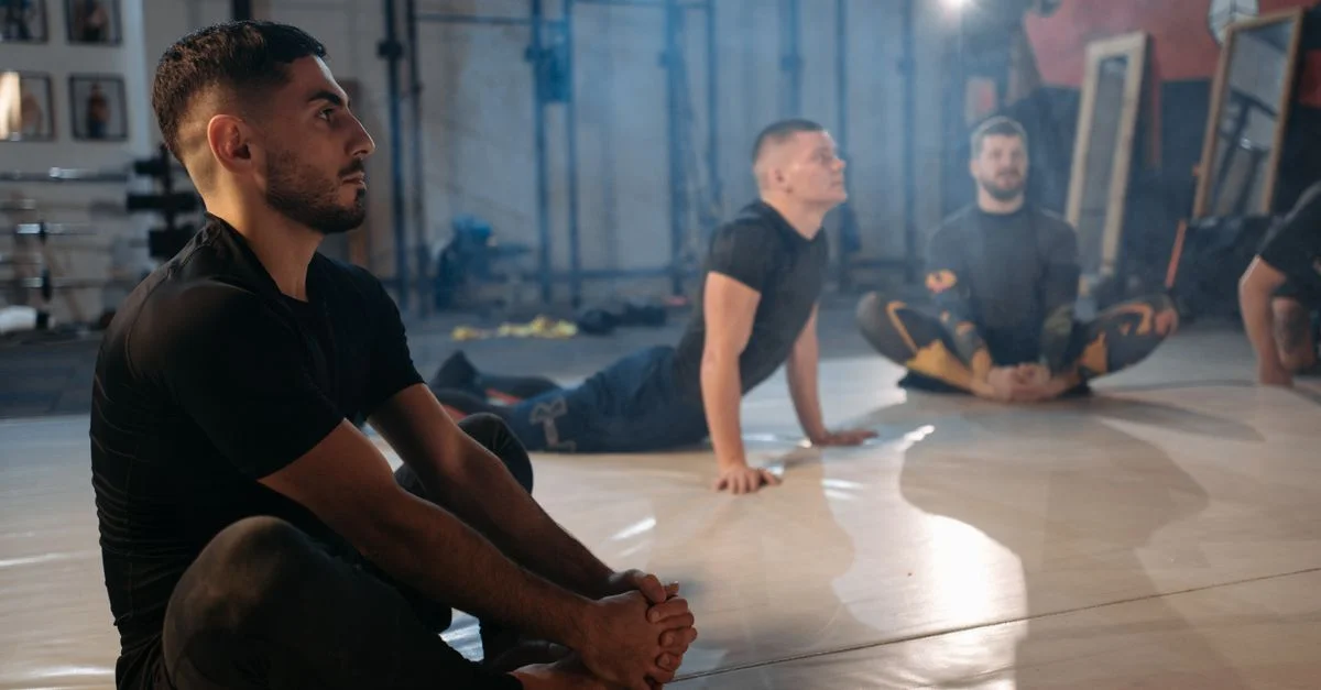 Des hommes pratiquent des exercices d'étirement dans une salle de sport, mettant l'accent sur la flexibilité et la forme physique.