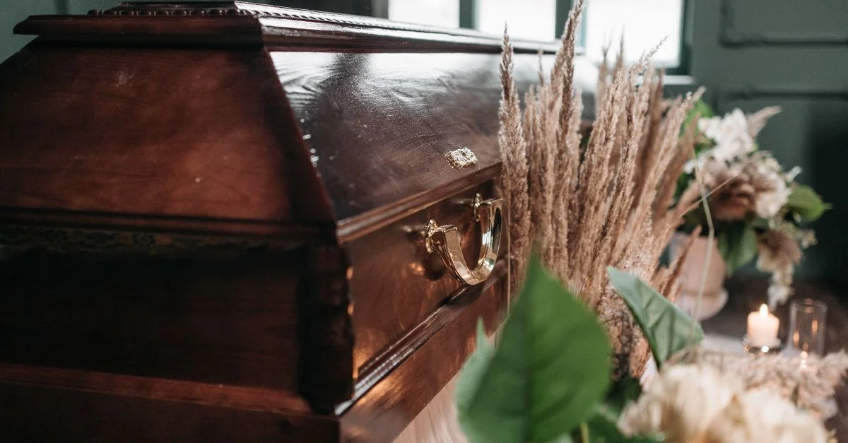 Une belle exposition funéraire présentant un cercueil en bois avec des fleurs et des bougies à l'intérieur.