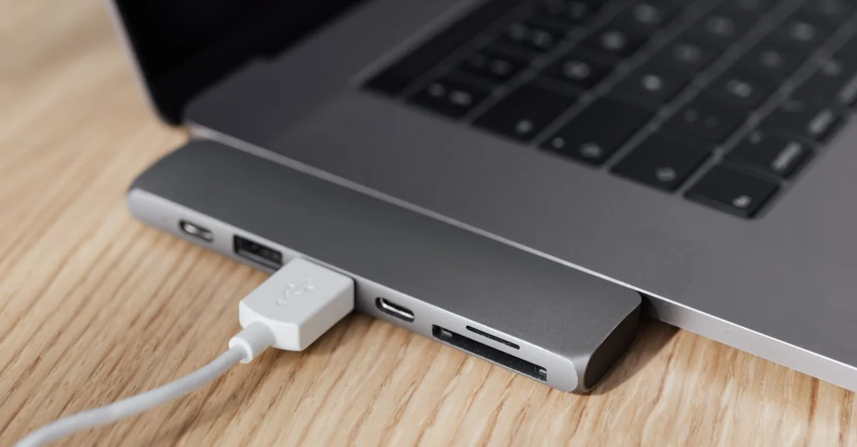 Un élégant hub USB-C connecté à un ordinateur portable sur un bureau en bois, idéal pour les configurations technologiques.