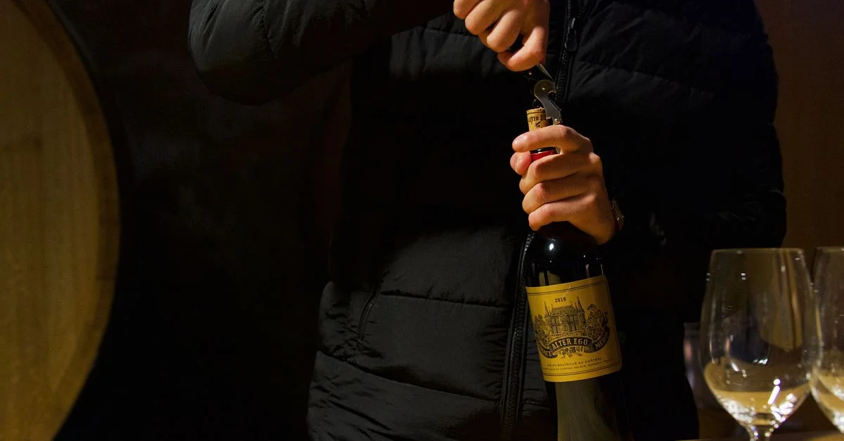 Personne débouchant une bouteille de vin à Margaux, Bordeaux. Dégustation de vin élégante dans une cave française.