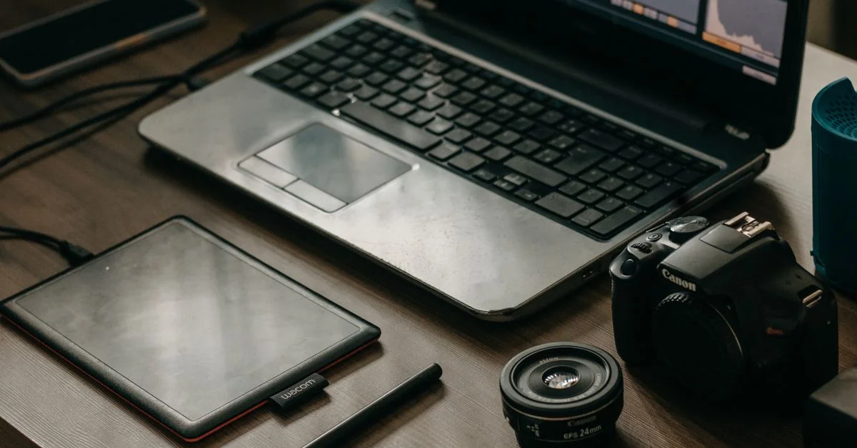 Ordinateur portable, appareil photo, objectif et tablette graphique sur un bureau pour les créatifs numériques.
