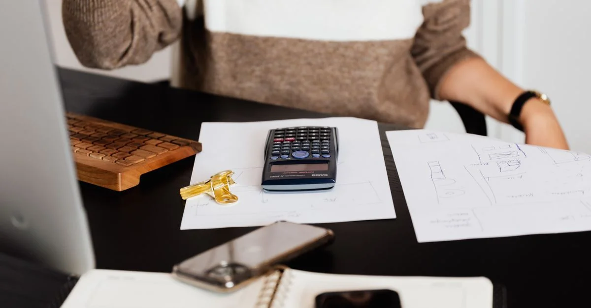 Un bureau d'affaires avec une calculatrice, des papiers et un clavier, reflétant un environnement de travail.