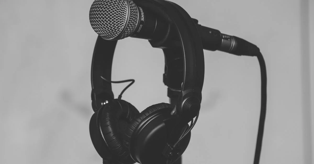 Gros plan noir et blanc d'un microphone et d'un casque sur un support, parfait pour des thèmes de musique et de studio d'enregistrement.