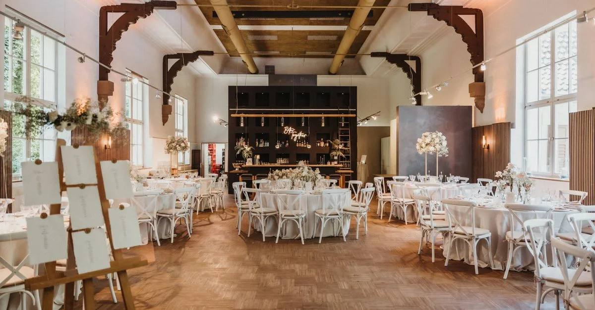 Salle de banquet spacieuse préparée pour un mariage avec des arrangements de tables et de chaises élégants.