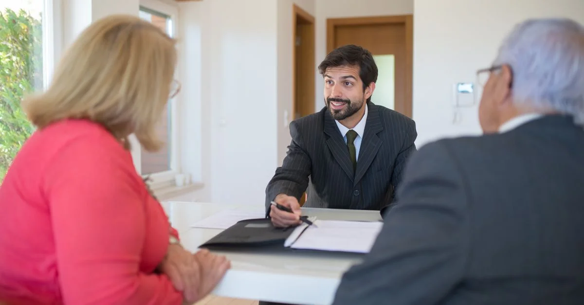 Un agent immobilier discutant d'un contrat avec des clients seniors dans un bureau.