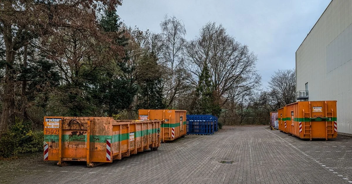 Vue extérieure de conteneurs à déchets industriels alignés à côté d'un entrepôt en hiver.
