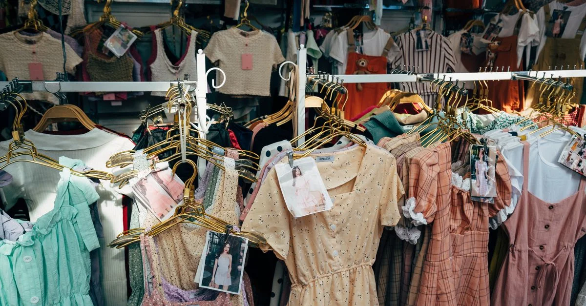 Un assortiment coloré de robes suspendues sur un portant dans une boutique de mode tendance.