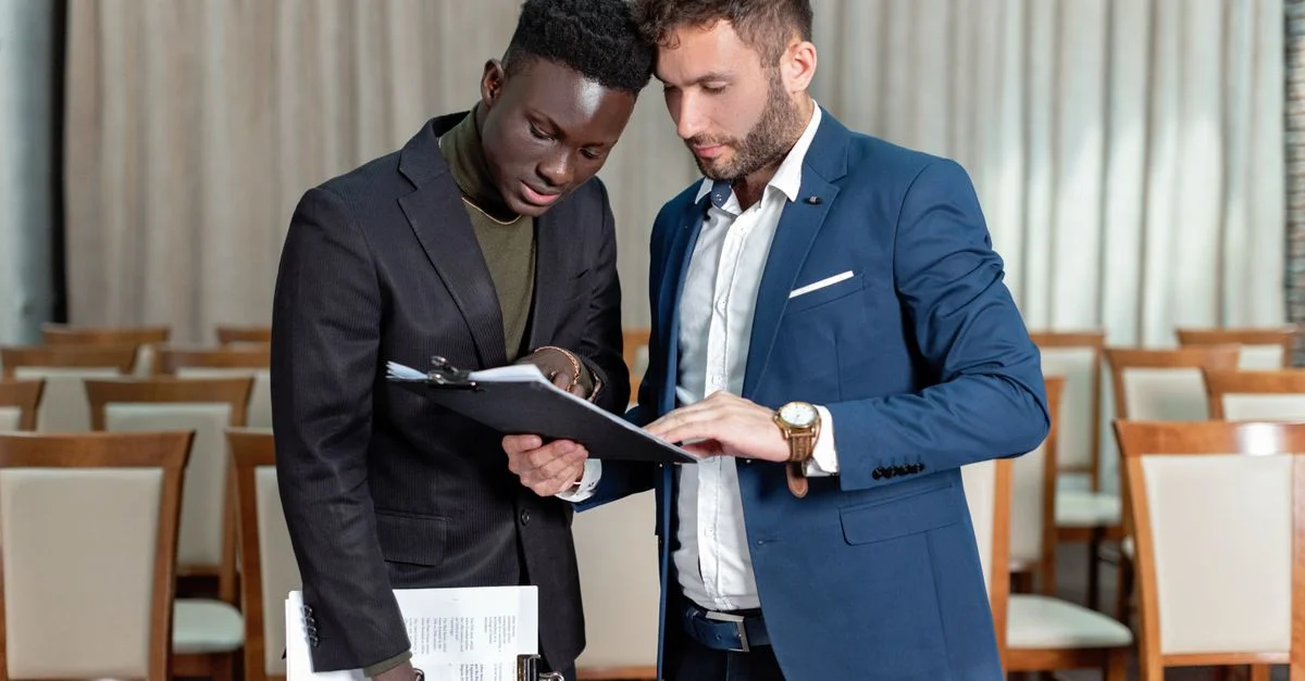 Deux professionnels en affaires engagés dans l'examen détaillé d'un document dans une salle de conférence.