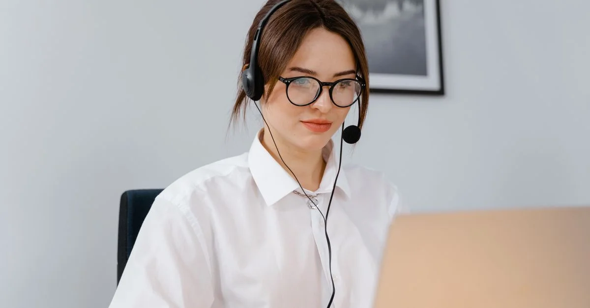 Femme avec un casque travaillant sur un ordinateur portable en tant que support client dans un environnement de bureau.