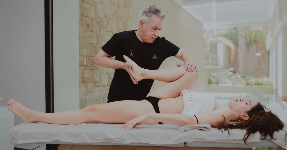 Un thérapeute assiste un patient lors d'une séance de rééducation en intérieur, favorisant la mobilité et la flexibilité.