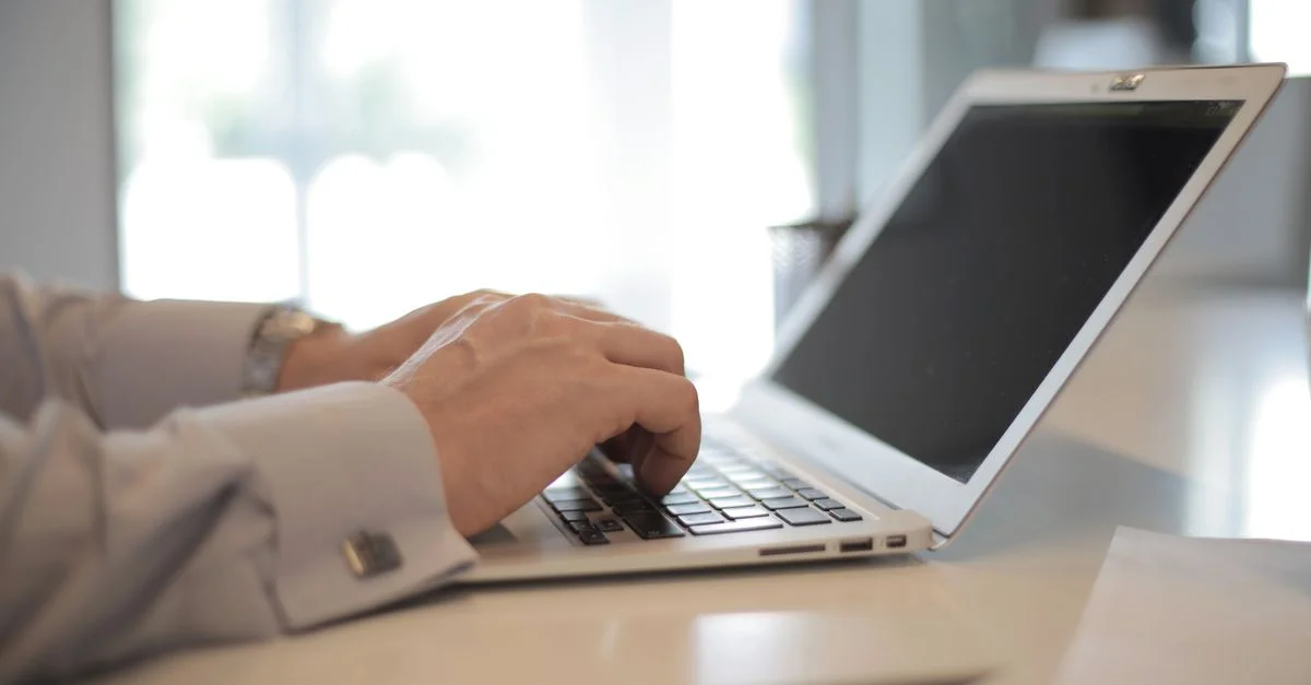 Gros plan sur des mains tapant sur un ordinateur portable dans un bureau moderne et lumineux.