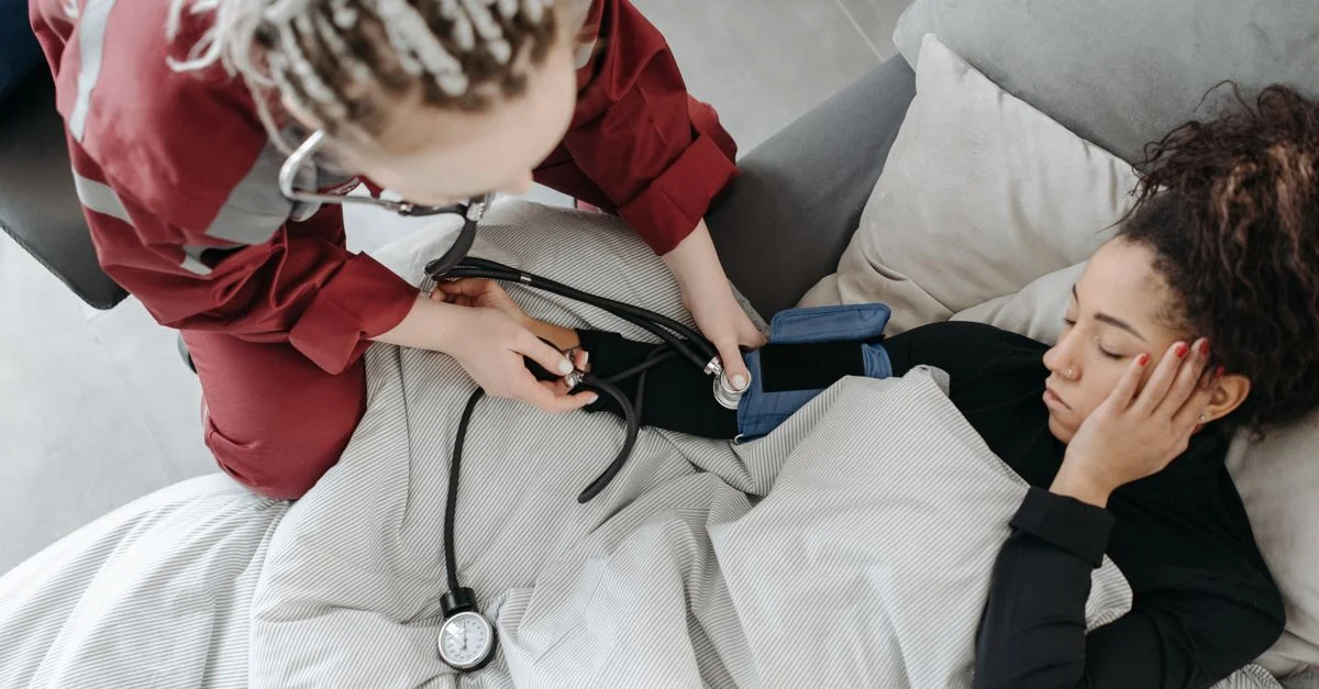 Paramédic mesurant la pression artérielle du patient à l'intérieur, illustrant l'assistance aux soins à domicile.