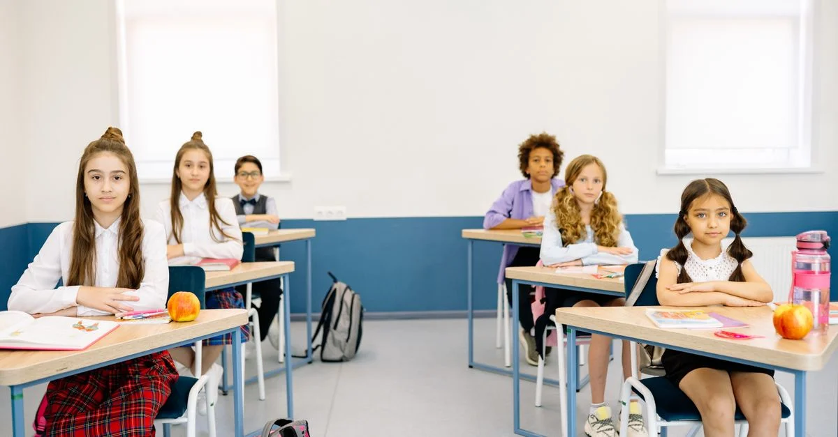 Des enfants étudiant attentivement dans une salle de classe lumineuse, promouvant des environnements d'apprentissage diversifiés.