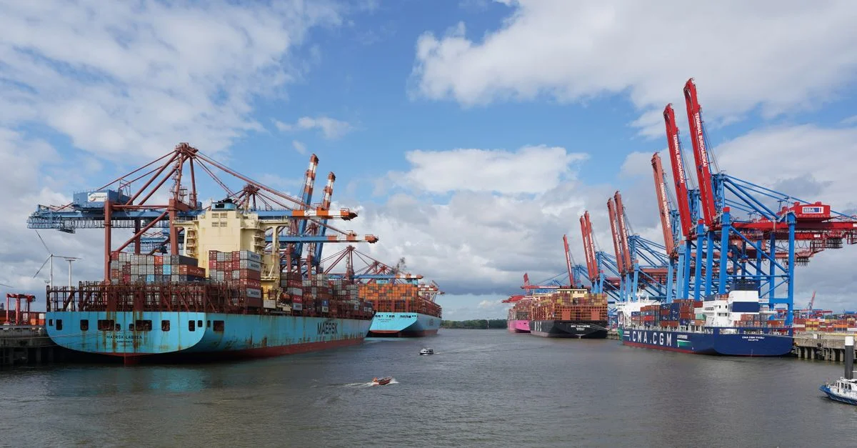 Une vue vibrante de bateaux de conteneurs au port de Hambourg sous un ciel bleu.