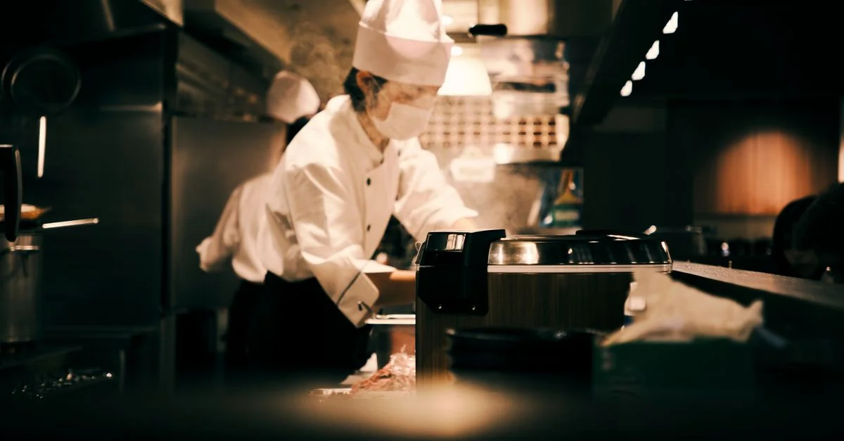 Un chef en uniforme travaille assidûment dans une cuisine animée de restaurant japonais à Osaka, Japon.