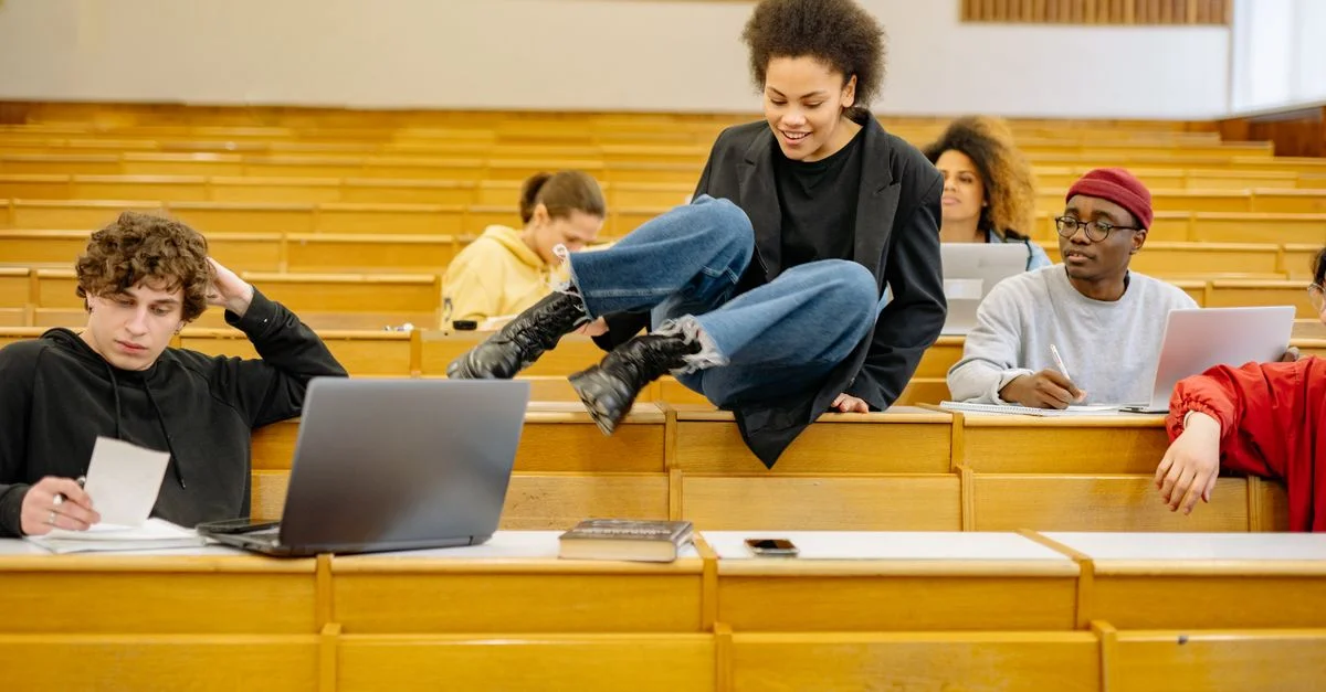 Des étudiants divers interagissent et étudient dans un amphithéâtre universitaire.