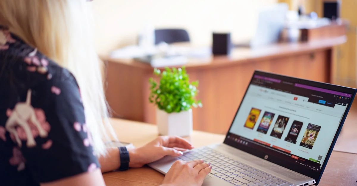 Une femme naviguant sur un magasin en ligne sur un ordinateur portable dans un bureau moderne.