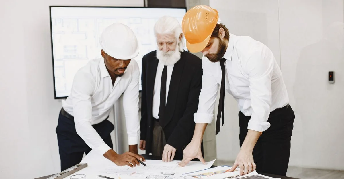 Trois professionnels dans un bureau examinant des plans de construction et collaborant sur un projet de construction.
