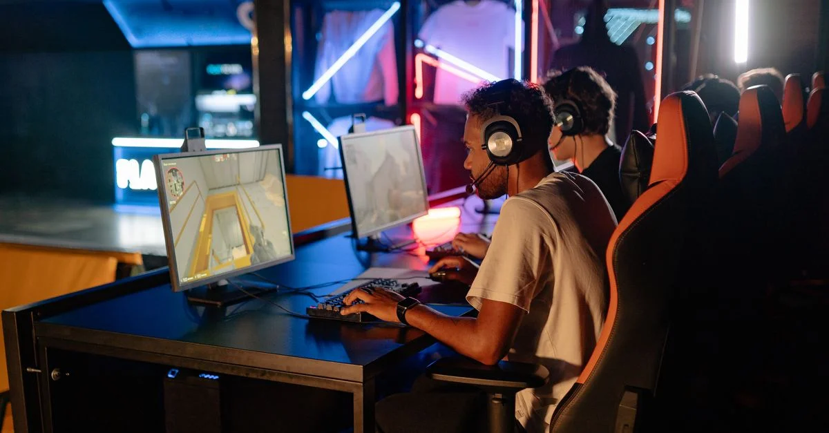 Session de jeu compétitif entre amis à l'intérieur avec des ordinateurs high-tech et des lumières néon.
