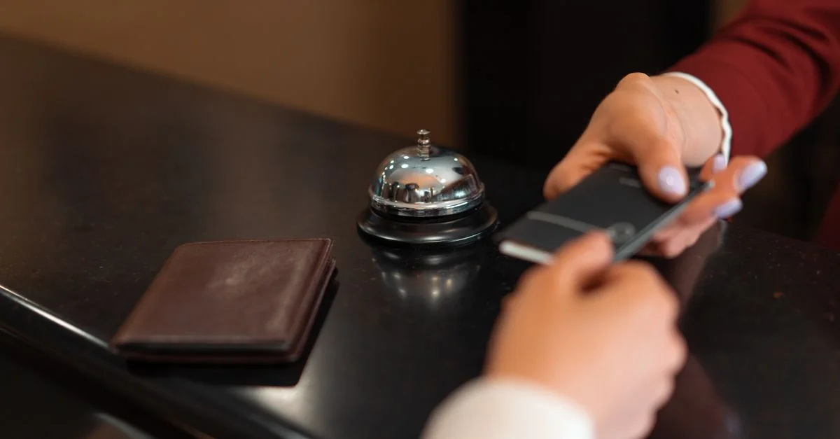 Un gros plan du processus d'enregistrement à l'hôtel avec un smartphone et une transaction par carte à la réception.