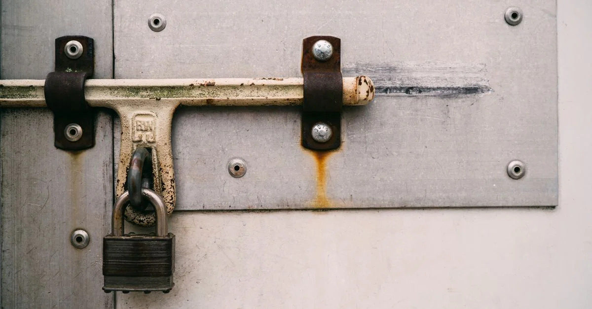 Gros plan sur un cadenas rouillé sécurisant une porte en métal, soulignant la sécurité et la protection.