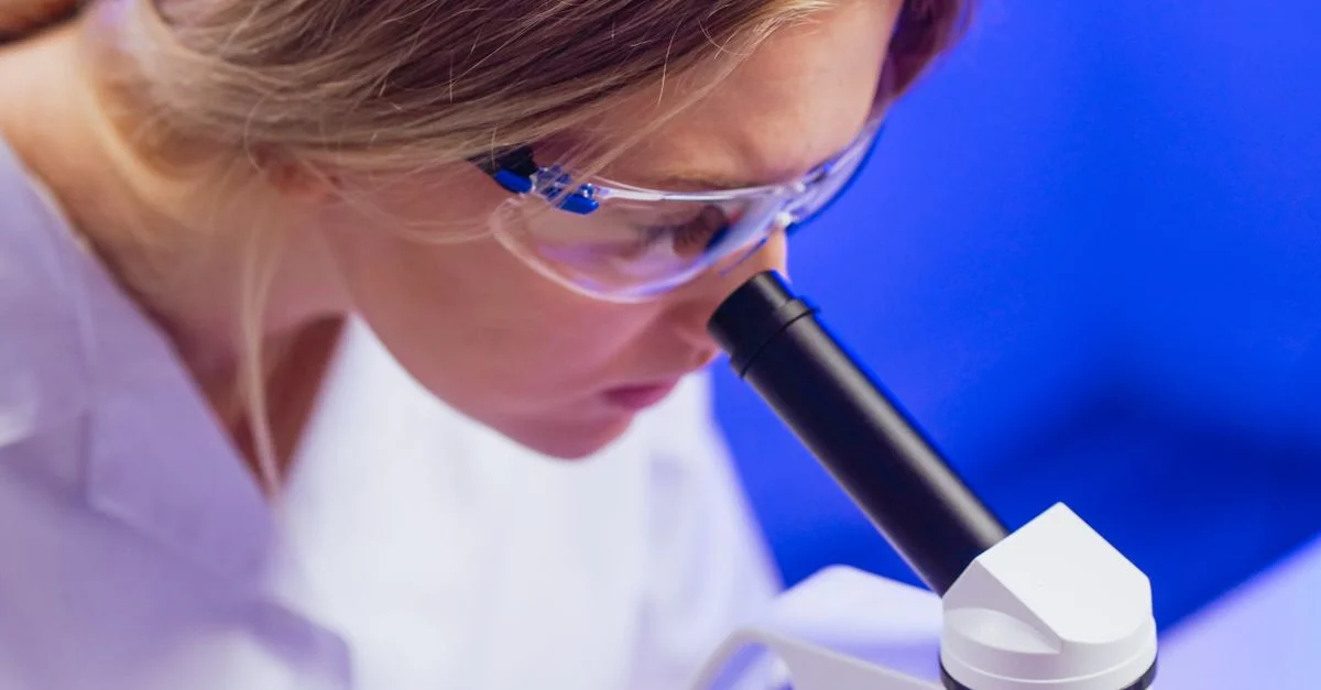 Scientifique féminine concentrée utilisant un microscope dans un laboratoire.