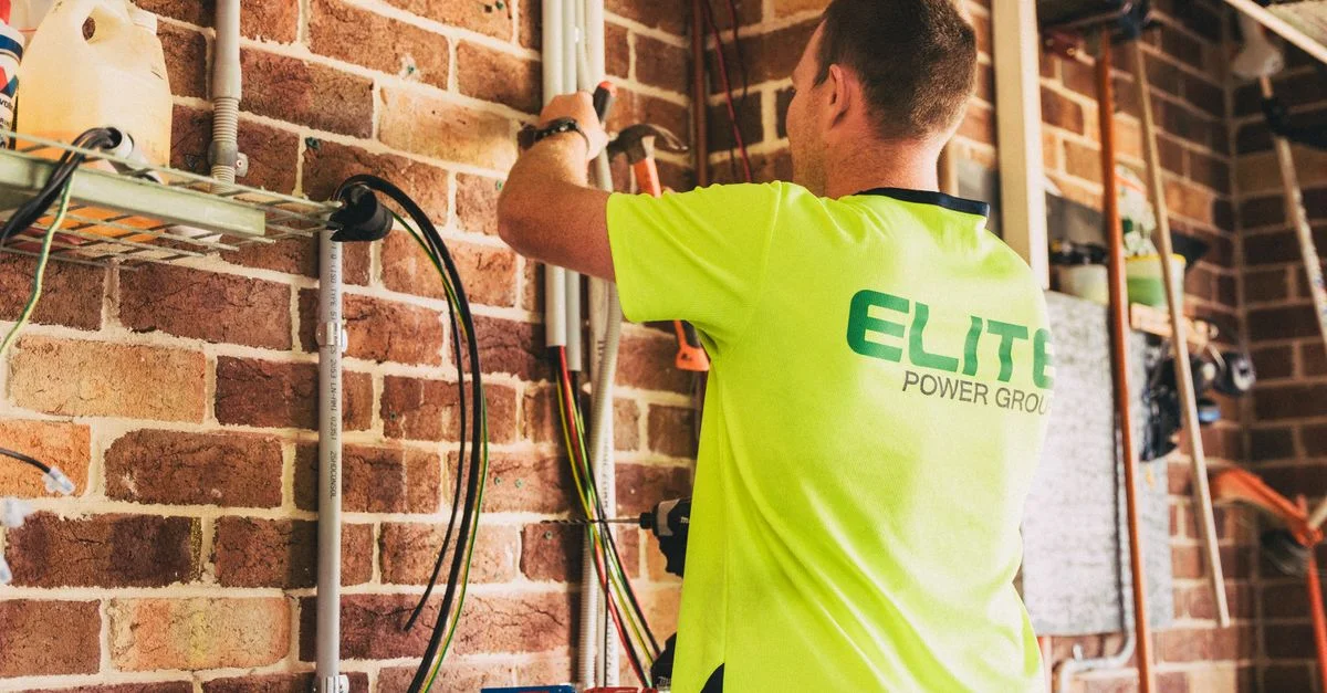 Électricien réalisant l'installation d'un système de stockage d'énergie solaire durable pour une habitation.
