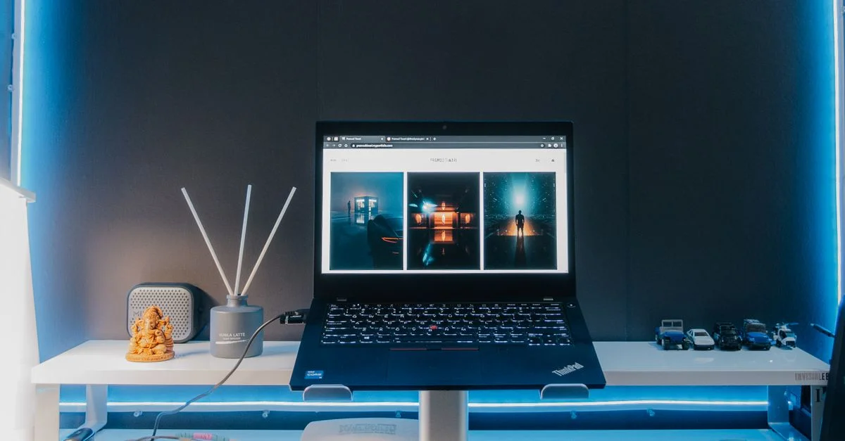 Configuration de bureau contemporaine avec un ordinateur portable, des accessoires électroniques et un éclairage néon pour un espace de travail élégant.