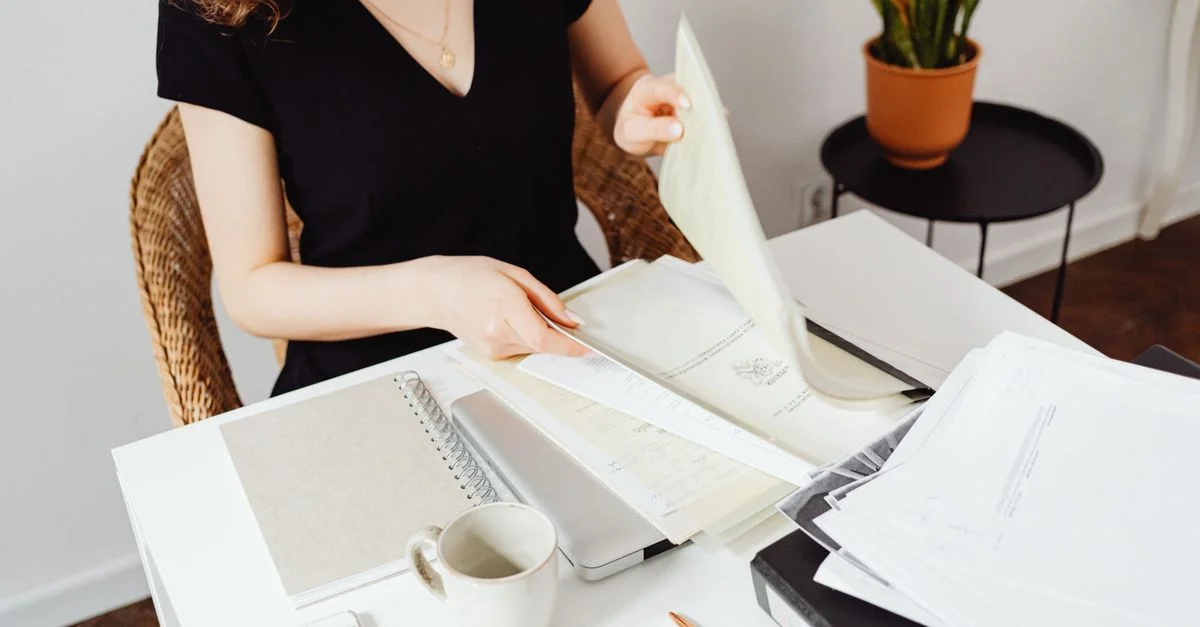 Femme triant des documents dans un bureau à domicile. Espace de travail organisé avec des plantes.