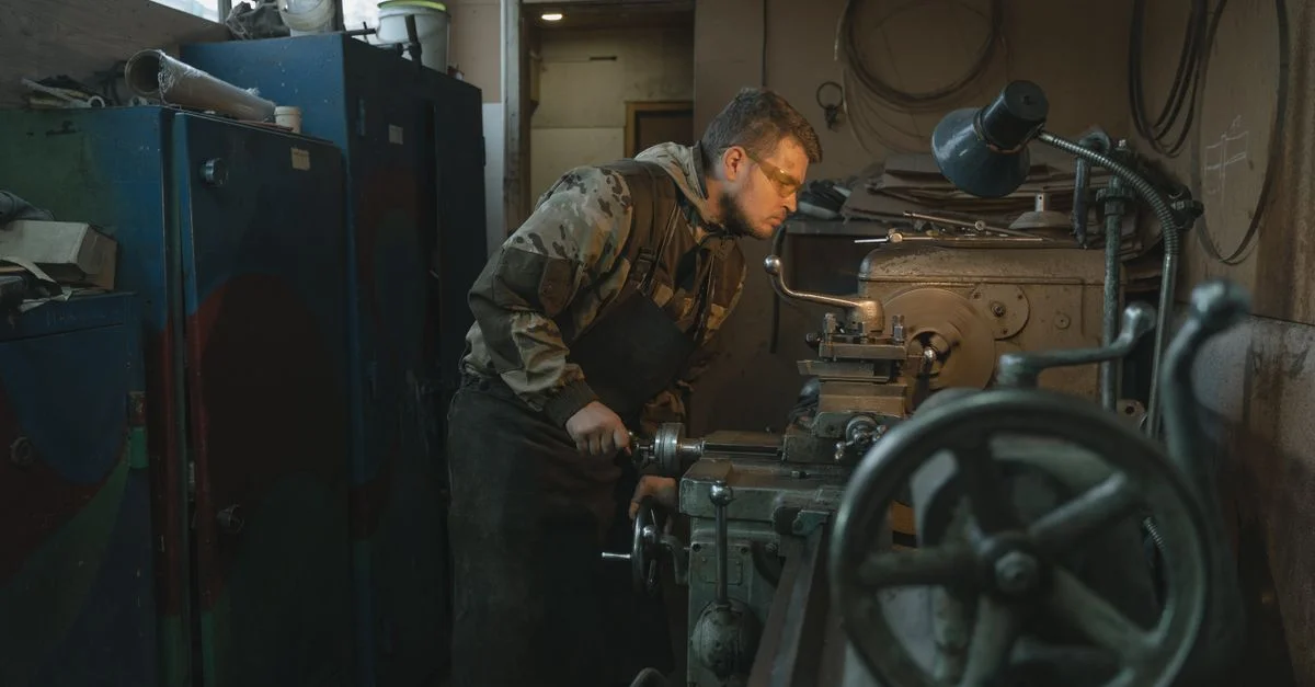 Homme caucasien opérant un tour dans un atelier industriel, concentré sur un travail de précision.