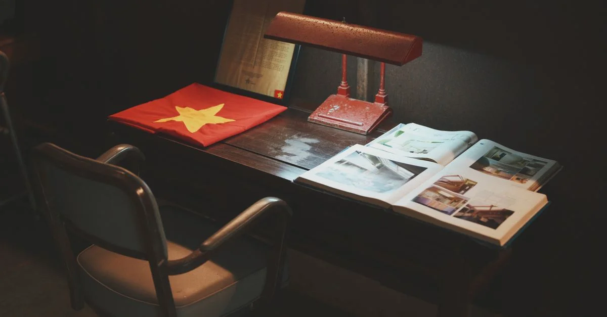 Un bureau rustique aménagé avec un drapeau coloré, une lampe vintage et des livres ouverts, créant une atmosphère d'étude empreinte de nostalgie.