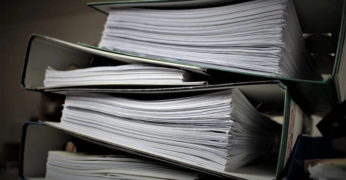Gros plan sur des classeurs empilés remplis de documents pour un usage de bureau ou éducatif.